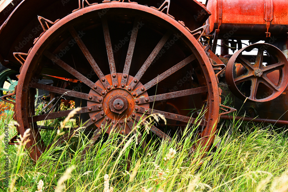 An mage of an old rusted metal tire on a vintage tractor.  