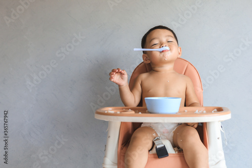 Asian baby boy eating food by himself