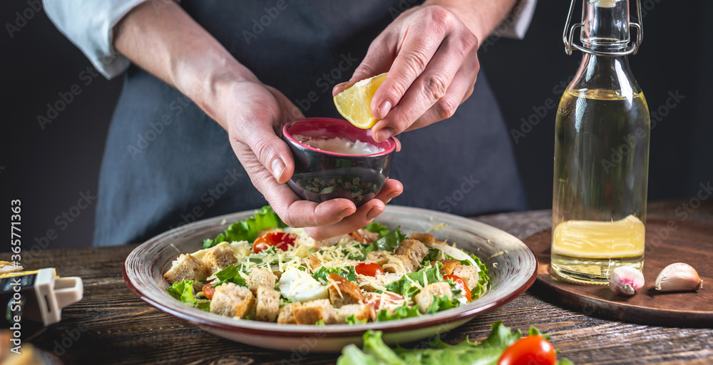 Chef is squeezing out a lemon to make a special sauce. Concept of cooking a fresh and delicious Caesar salad