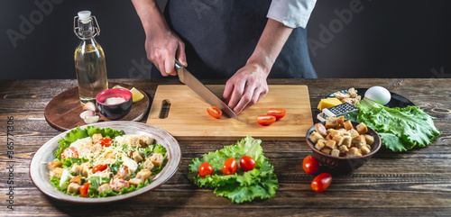 Chef is cutting the tomatoes. Concept of the process of preparing a fresh delicious salad