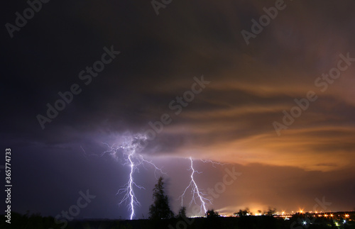 night storm with lightning against the background of light from a chemical plant