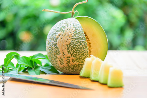 Fresh green melon with liverpool logo on wood plate photo