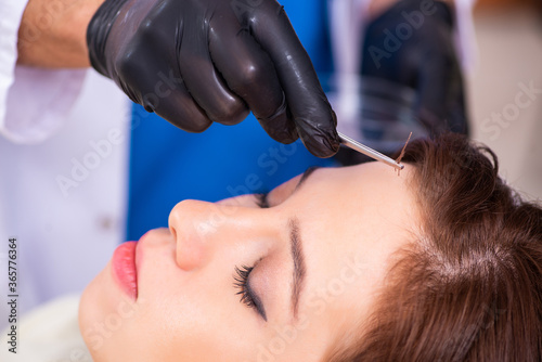 Young woman visiting male beautician in hair transplantation con