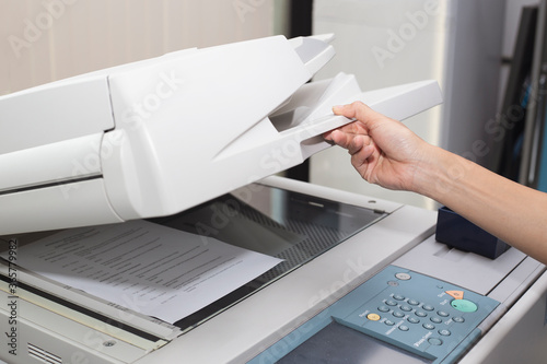 Photography woman hands putting a sheet of paper into a copying device or printer in the off