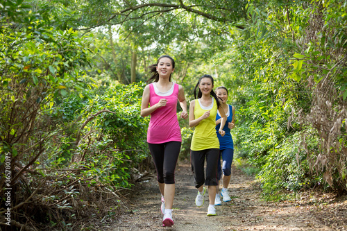 Three female friends running together on the path