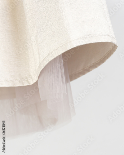 Detail of a golden skirt with a beige petticoat