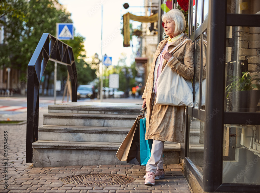 Obraz premium Senior Caucasian woman strolling on city street after shopping