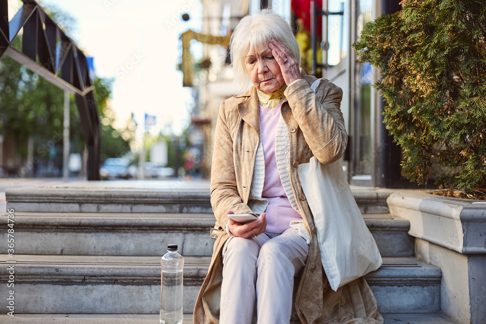 Fototapeta premium Portrait of an attractive senior woman sitting on a steps
