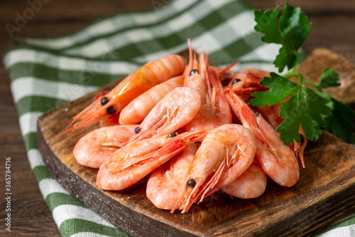 Shrimp on a wooden Board on a brown wooden table. Lots of prawns on the serving Board. Prawns close up