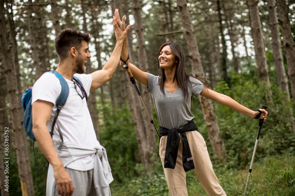 Smiling young couple walking with backpacks in the forest Smiling young couple walking with backpacks in the forest