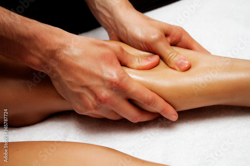 Lymphatic drainage massage of legs and lower legs. Female feet in the hands of a masseur.