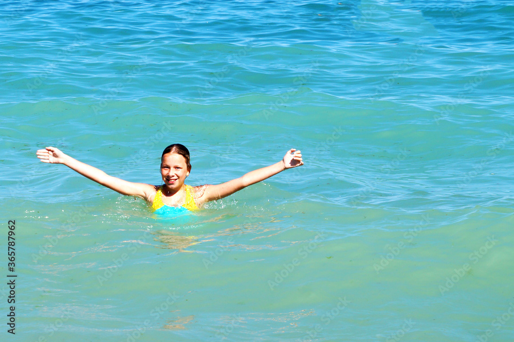 girl with hands up smiling at sea