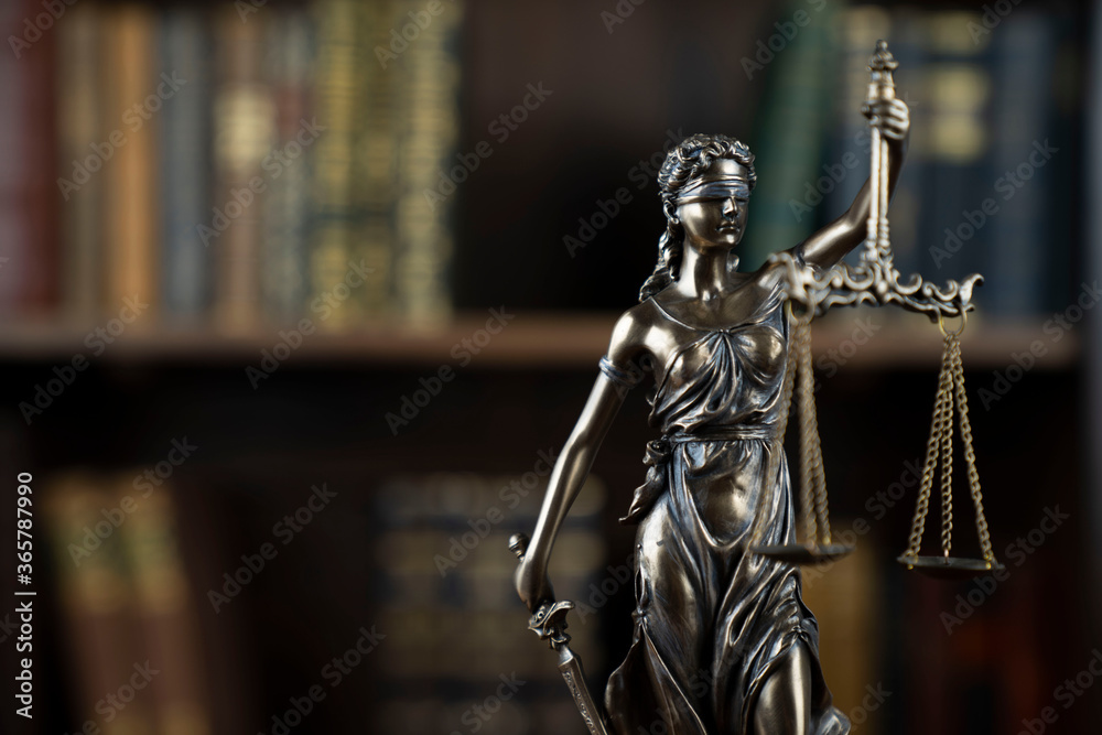 Law theme. Judge chamber. Themis statue on brown shining desk. Collection of legal books in the bookshelf. Law theme. Judge chamber. Themis statue on brown shining desk. Collection of legal books in the bookshelf.