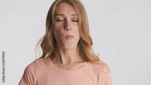 Portrait of young blond woman emotionally chewing on camera over gray background. Different face expressions photo