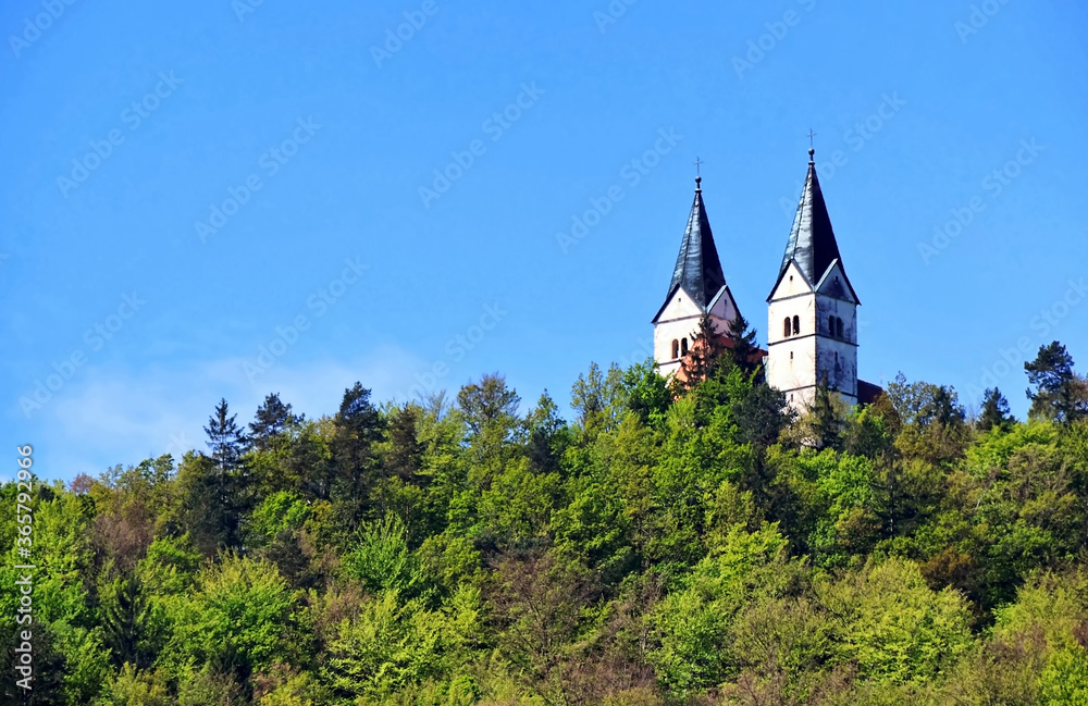 A view over roof of catholic church tower settled in forest at the top of the hill in Lasko, Slovenia.