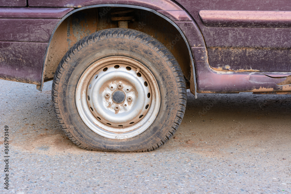 Damaged tire. The wheel of car tire leak. Flat tire waiting for repair. Abandoned car in the parking lot. Damaged tire. The wheel of car tire leak. Flat tire waiting for repair. Abandoned car in the parking lot.