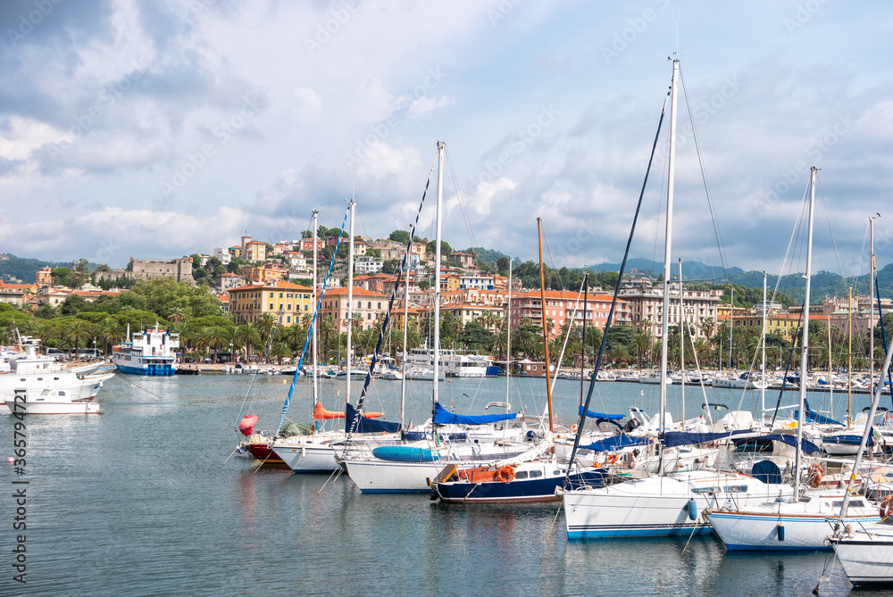 Beautiful landscape of La Spezia with bright italian houses and palm trees. View of the city port on the shores of the Ligurian Sea with boats in the foreground.