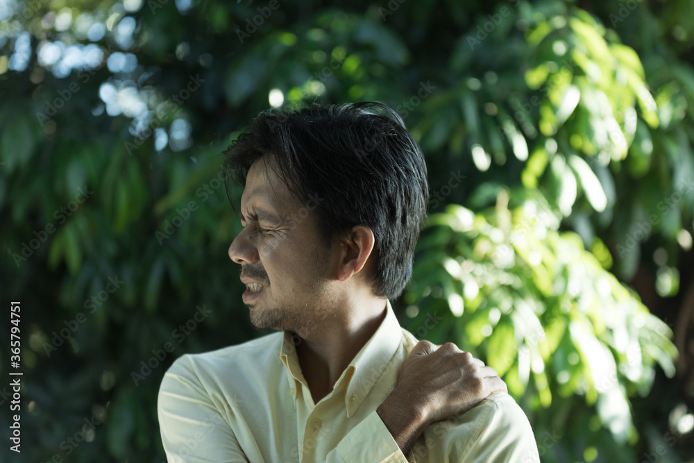 young asian man feeling the pain in shoulder young asian man feeling the pain in shoulder