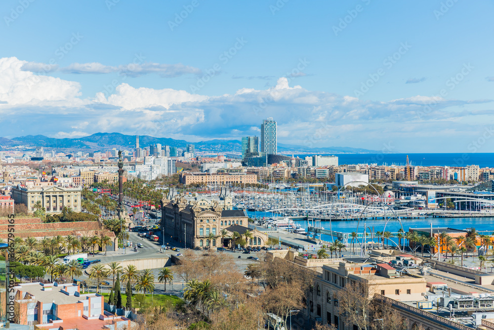 Cityscape of the port and part of the city of Barcelona, ​​wonderful sunny day with a blue sky and white clouds in Spain