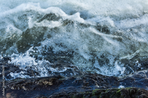 Closeup of moving ocean water with foam and small waves caused by wind and rain seen from a boat © Emile