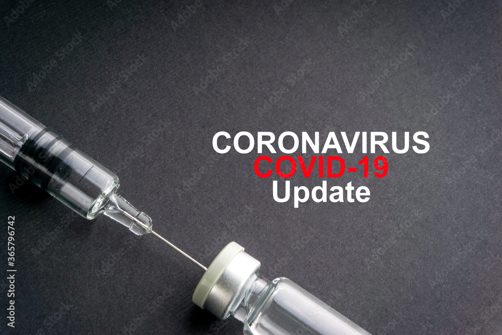 CORONAVIRUS COVID-19 UPDATE text with syringe and vials on black background. Covid-19 and Coronavirus concept CORONAVIRUS COVID-19 UPDATE text with syringe and vials on black background. Covid-19 and Coronavirus concept