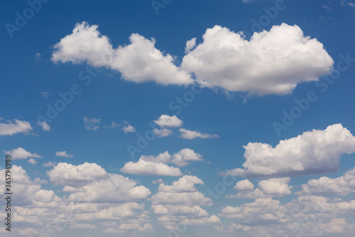 many white cumulus clouds in the blue sky, in the foreground a large long cloud, landscape