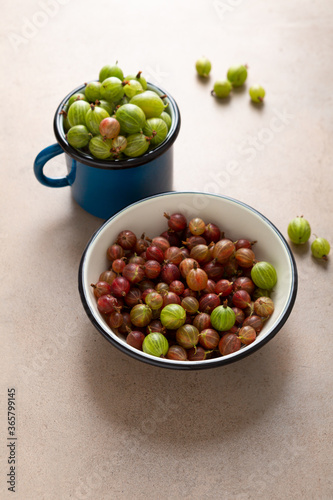 Fresh red and green gooseberry in bowl and in mug