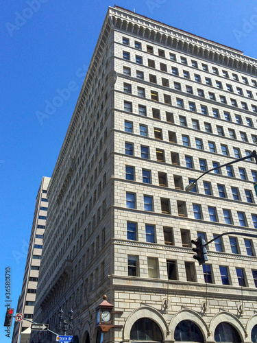 The square building with 12 floors in San Diego city on the corner of the street. Nice looking building in california at the intersaction.