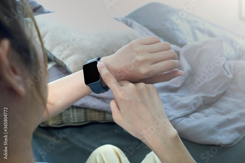 Closeup image of a woman using wireless Smart Watch on sofa
