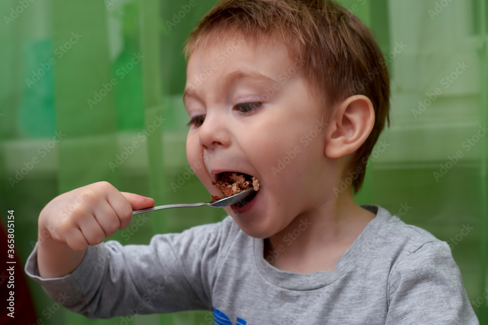 Portrait of a two year old beautiful child. Child eating chocolate cake with a teaspoon Portrait of a two year old beautiful child. Child eating chocolate cake with a teaspoon