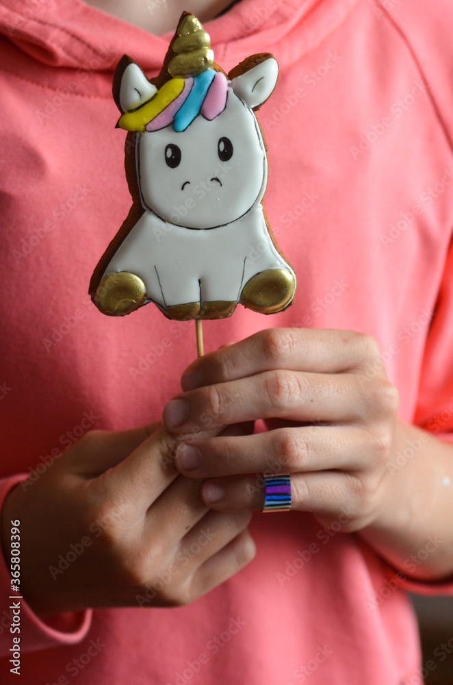 Gingerbread in the shape of a unicorn in the hands of a child. Treats for a children's holiday