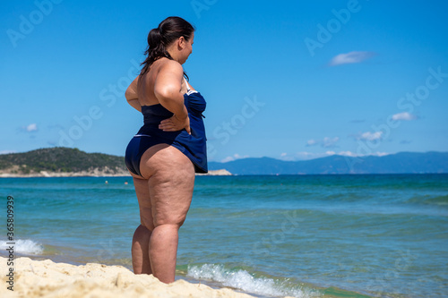 Body positive. Happy fat woman on the beach. Full-length photo. Back view