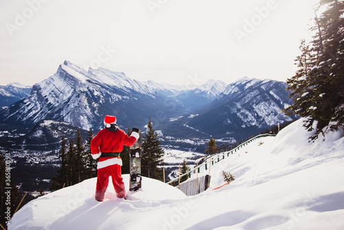 Santa with snowboard looking over mountains