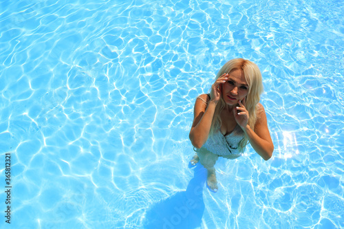 Top view of young girl in swimming pool against blue water background