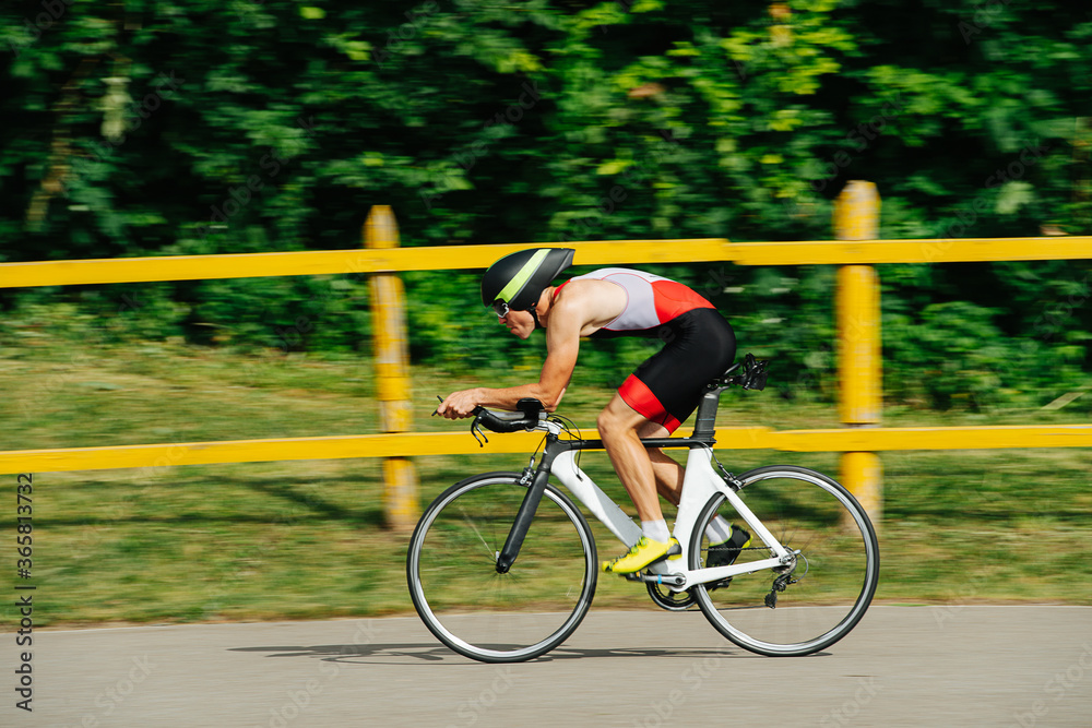 Naklejka premium Athlete in low posture riding on a pro bike with streamlined helmet. Side view.