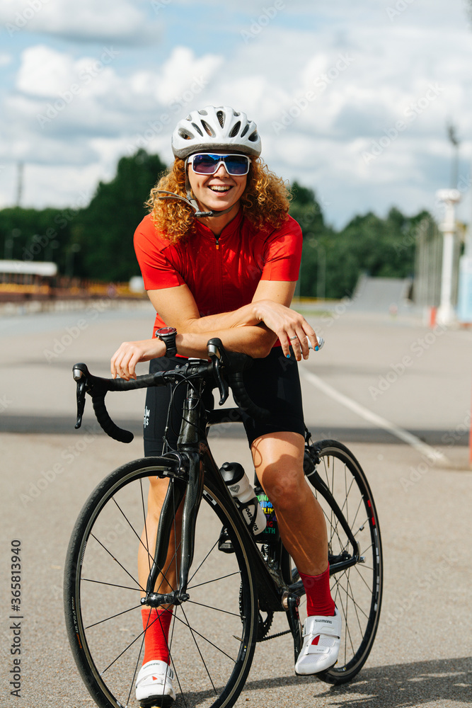 Charmingly smiling beautiful woman on a pro bike on a road. Charmingly smiling. Charmingly smiling beautiful woman on a pro bike on a road. Charmingly smiling.