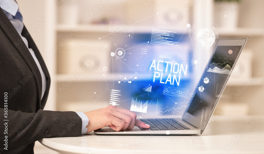 Side view of a business person working on laptop with ACTION PLAN inscription, modern business concept