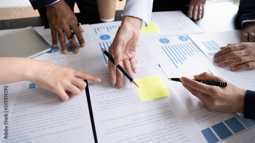 фотографія Diverse corporate staff discuss report shown in charts and graphs, analyzing financial stats, involved in project overview, reviewing results, close up
