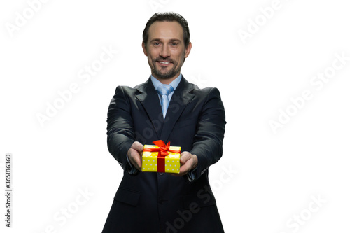 Smiling chief in costume giving a present. Middle-aged director holding a present in yellow box. Succesful european man isolated on white background.