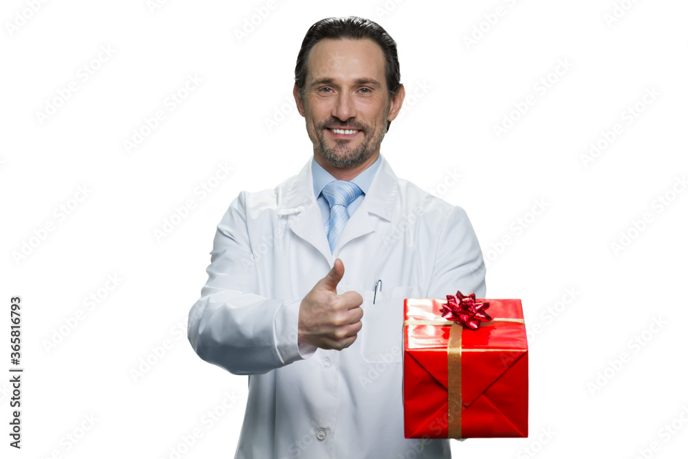 Portrait of american doctor holding a present. Cheerful medic giving a thumb up. Handsome doctor isolated on white background. Portrait of american doctor holding a present. Cheerful medic giving a thumb up. Handsome doctor isolated on white background.