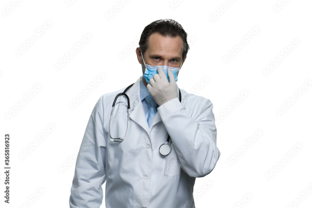 Mature american doctor with stethoscope touching his respirator mask. Successful medic in white robe isolated on white background. Mature american doctor with stethoscope touching his respirator mask. Successful medic in white robe isolated on white background.