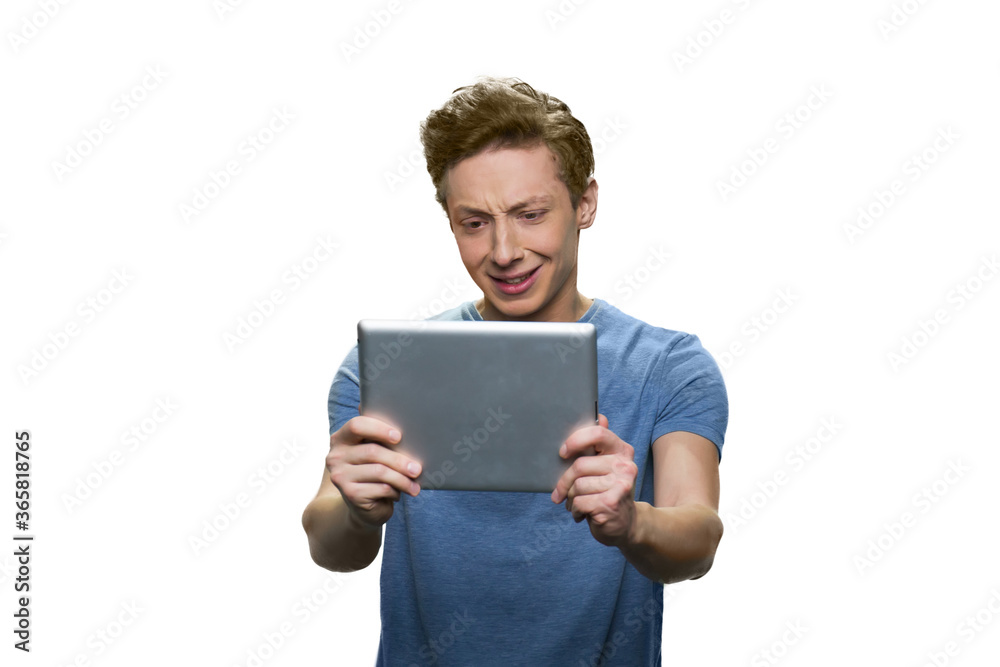 Teen skinny guy is holding tablet pc. Facial expression of discontent. Isolated on white background. Teen skinny guy is holding tablet pc. Facial expression of discontent. Isolated on white background.