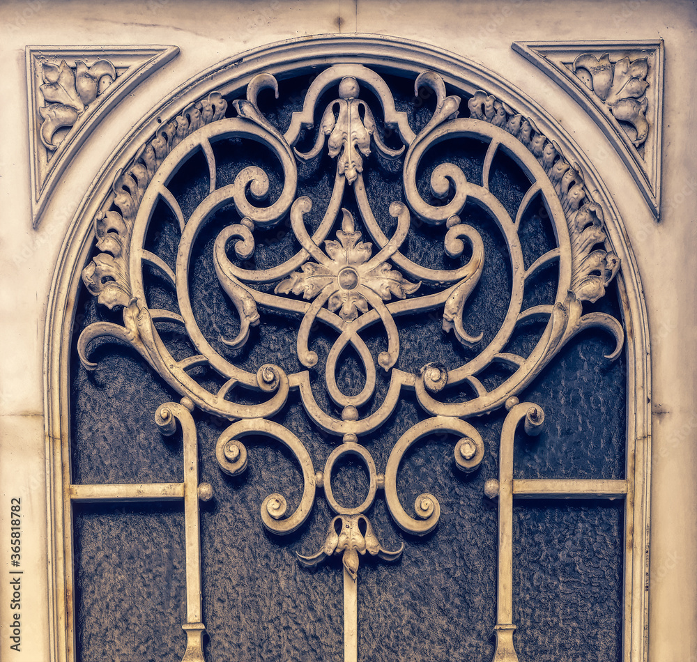 Old metal decorative element as cover for window on entrance door.