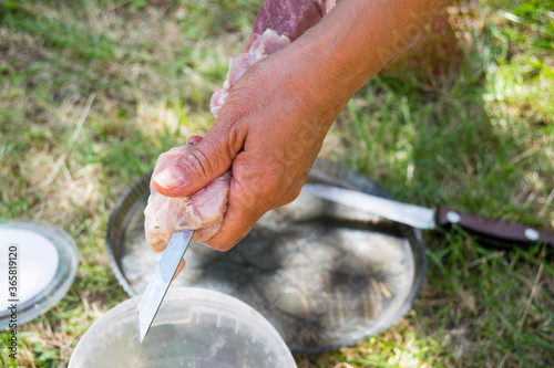 Hand string raw meat on a skewer. A person prepares shashlik. Closeup.