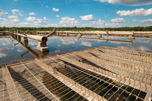 Dukora Belarus Minsk Region. Thermal energy electricity station plant cooling system fountains and lake in sunny summer warm weather. Blue sky and clouds reflecting in the water. Nature and industry photo