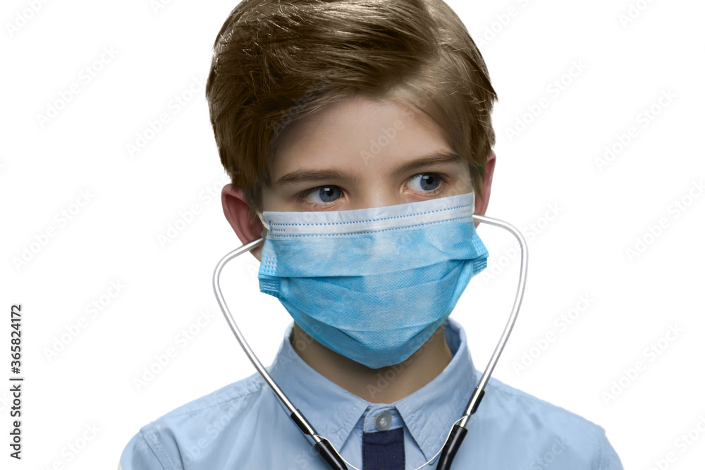 Portrait of young boy in medical mask and stethoscope. Protection during the quarantine. Child doctor against white background. Portrait of young boy in medical mask and stethoscope. Protection during the quarantine. Child doctor against white background.