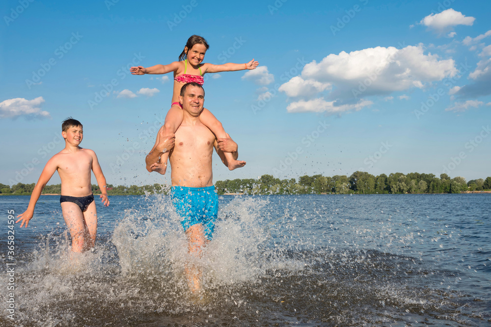 Naklejka premium Father with children jumping together in the water at the beach. Vacation, leisure, way of life. The concept of sport and active play in the summer.