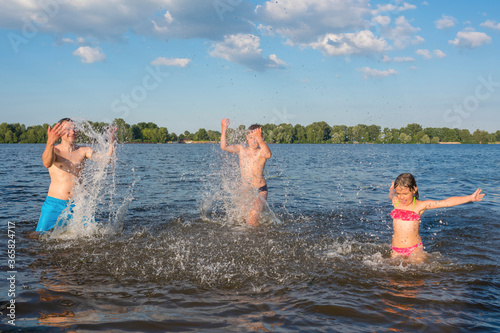 Happy family splashing water and having fun. Family summer vacation and water activities for children. © Andrii