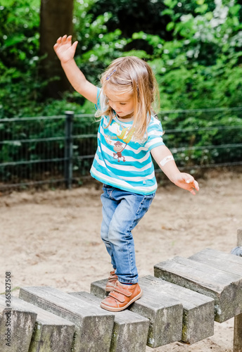 Toddler girl walking on wooden playground equipment