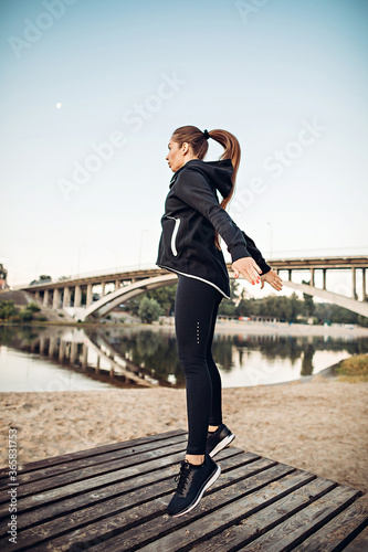 Girl jumping on wooden platform on river coast